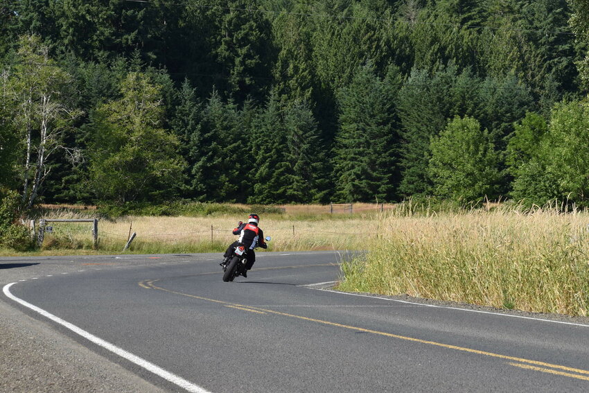 A motorcyclist makes a sharp right turn toward Oakville on Garrard Creek Road in southeast Grays Harbor County. Following construction, the road will continue straight, through the sheep pasture, before a more gradual hook to the right.