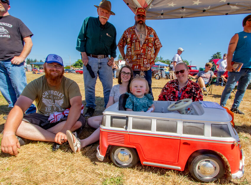 Olivia Emery-Martin sits in her RC Volkswagen Bus toy at the Toledo Cheese Days Car Show last Saturday. Behind her, sitting on the ground and starting on the left, are Olivia's parents, Brandon and Megan Emery-Martin, and her grandmother, Becky Martin. Standing behind them, starting on the right, is Olivia's grandfather, Jim Martin, and her great-grandfather, Gary Cadwell.
