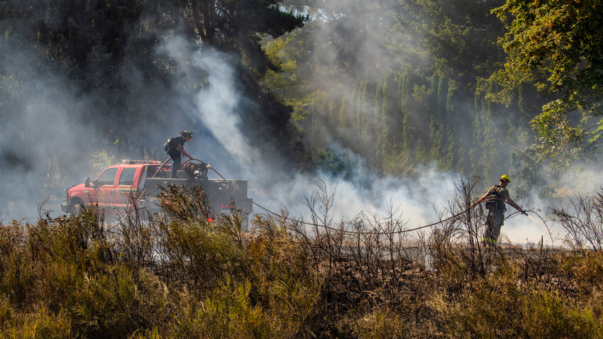 Lewis County firefighters use lines of hose to douse hot spots off state Route 6 near Claquato on Tuesday, July 18.