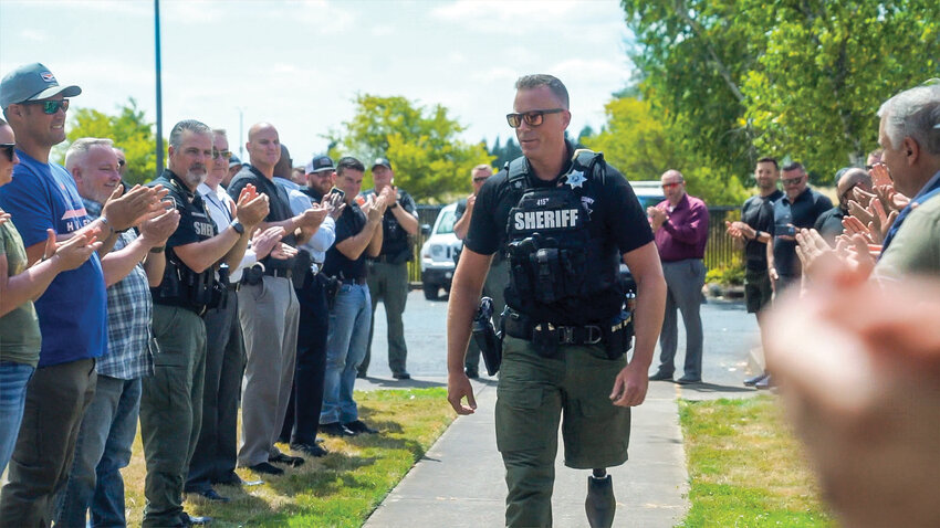 Clark County Sheriff&rsquo;s Deputy Drew Kennison is greeted as he returns to work July 25. Kennison&rsquo;s patrol SUV was crushed by part of a tree in Skamania County in February.