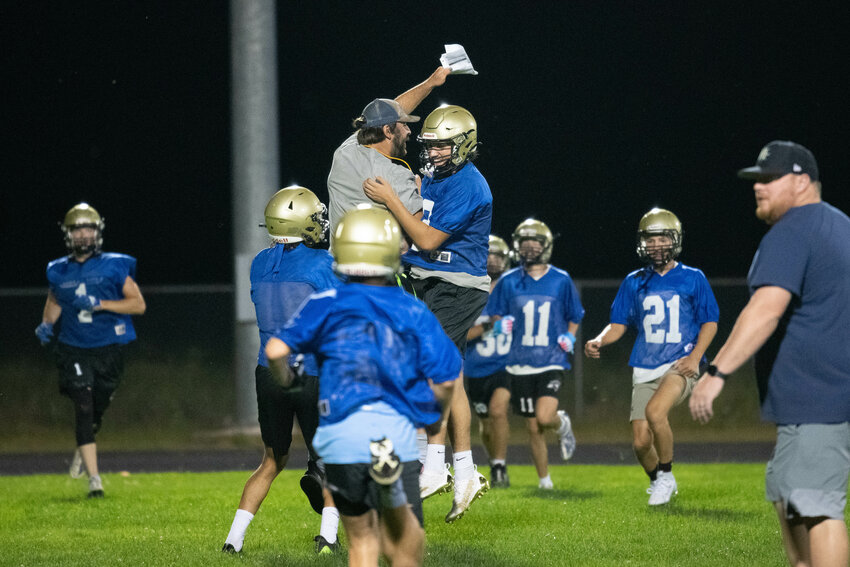 First-year Adna coach Aaron Cochran chest-bumps one of his players at the beginning of the Pirates' midnight practice to open training camp on Wednesday, Aug. 16.