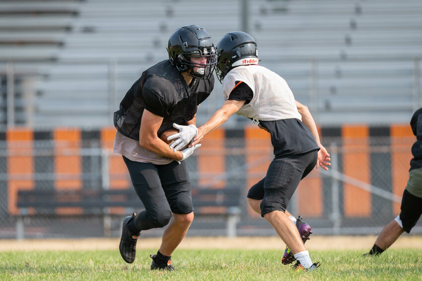 Jake Meldrum hands the ball off to Hunter Howell at Rainier's practice on Wednesday, Aug. 23.