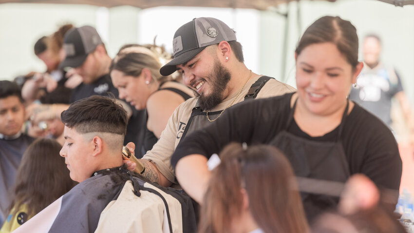 Organizer Alberto Isguerra, of Toro&rsquo;s Cuts, smiles while trimming the hair of visitors at a free back to school event featuring barbers from various local businesses at Tiger Stadium in Centralia on Friday, Aug. 25.