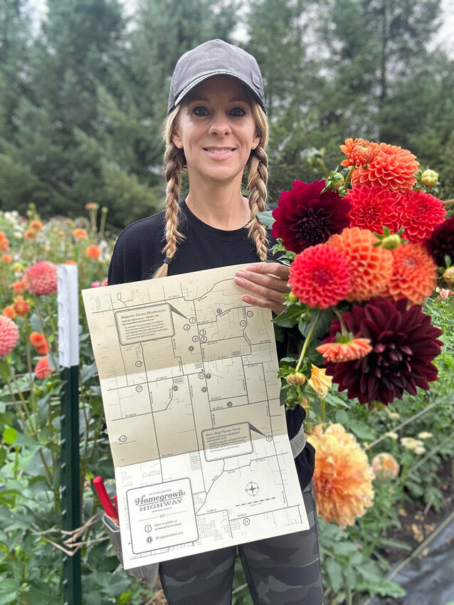 Tracy Hatcher, owner of Brush Prairie Flower Farm, holds the Hockinson Homegrown Highway Map in her field of flowers.