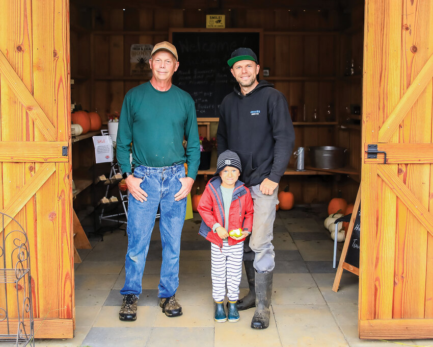 Owner of the La Center Gardens and Family Farm, John Parsons (left), stands with   Smart Bee Pollination owner Viktor Plyushchev (right) and his son Dimitry in front of the farmstand at Parsons&rsquo; farm.