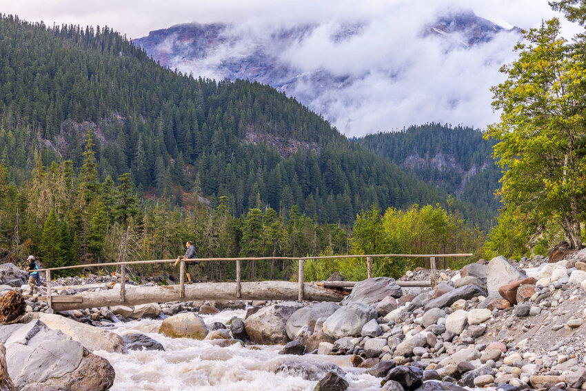 A man yells to his hiking partner to take his photo as he hangs over a foot bridge above the Nisqually River at Mount Rainier National Park on Tuesday, Sept. 12.