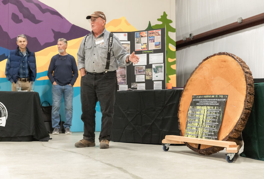 Bob Guenther talks about a slab of wood pulled from Iron Creek Campground during a Pinchot Partners celebration at Longmire Springs Brewing in Packwood on Wednesday, Sept. 20.