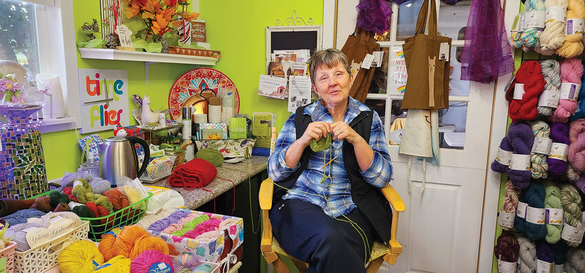 Pam Conrad, owner of Serendipity Alpaca Ranch, knits a green alpaca fiber scarf, a new item for the store.