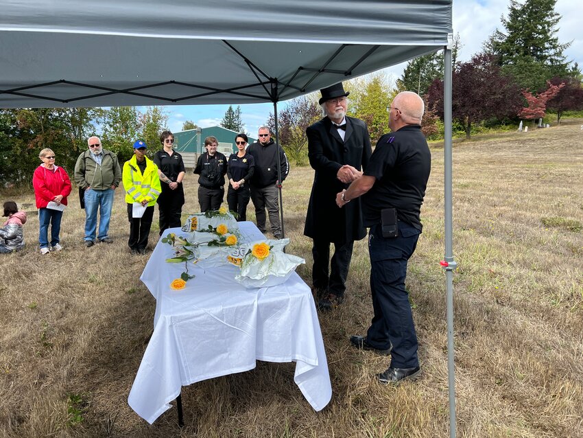 Lewis County Coroner Warren McLeod officially hands off the cremated remains of four people who died last year in Lewis County to John Panesko, owner of Pioneer Cemetery, where the remains will be laid to rest.