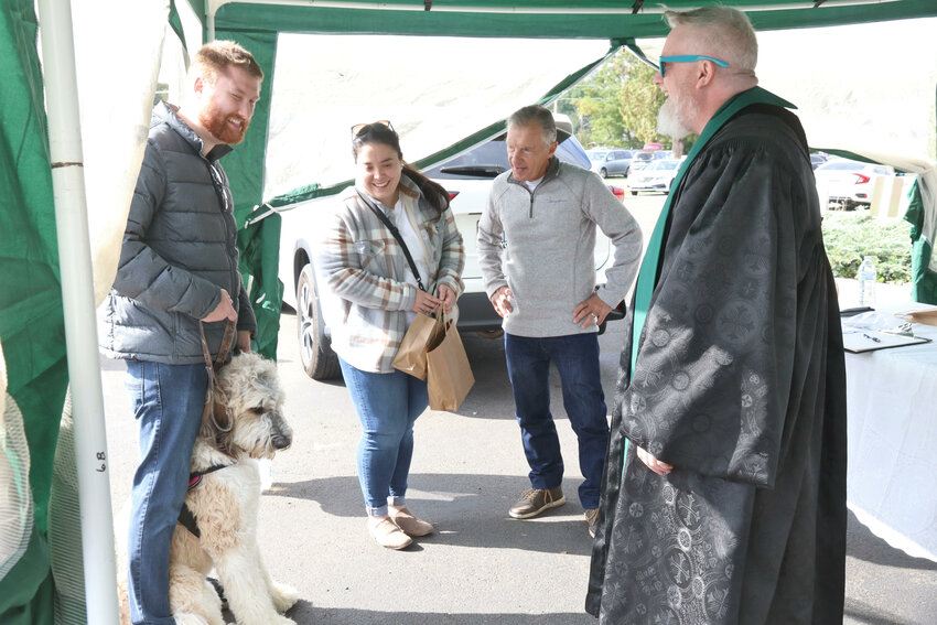 Pastor Zachary Taylor talks with dog owners Derek and Madison Johnston during a blessing for their dog, Remi, at the PAWchella pet fair outside the Veterans Memorial Museum in Chehalis on Saturday, Sept. 30.