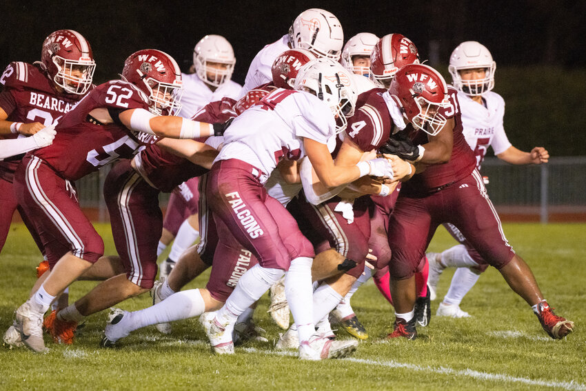 W.F. West quarterback Gage Brumfield (4) carries Prairie defenders as he marches down the field with the football alongside a team of blockers during a Friday night game in Chehalis.