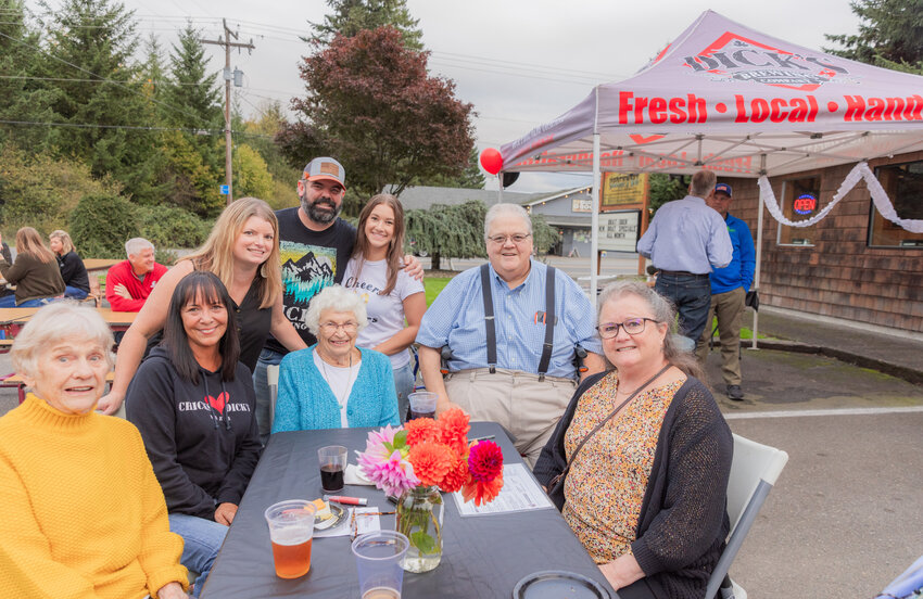 Back row, Julie and Dave Pendleton smile alongside Maddie McGregor and Daryl Lund as family members, from left, Jackie Creed, Lori Severns, June Young and Marilyn Gallagher pose for a photo at a table during Business After Hours at Dick&rsquo;s Brewing NW Sausage and Deli in Centralia on Thursday, Oct. 19.