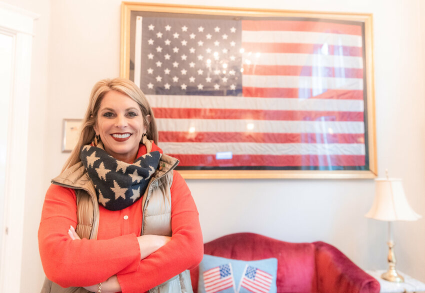 Leslie Lewallen smiles for a photo in front of a flag that flew over the White House during an interview at her Camas home.