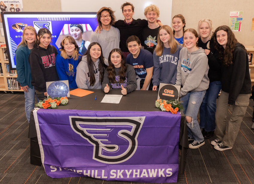 Chihiro Bringman smiles for a photo with fellow swimmers Tuesday evening at Centralia High School following her signing to Stonehill College in Massachusetts.