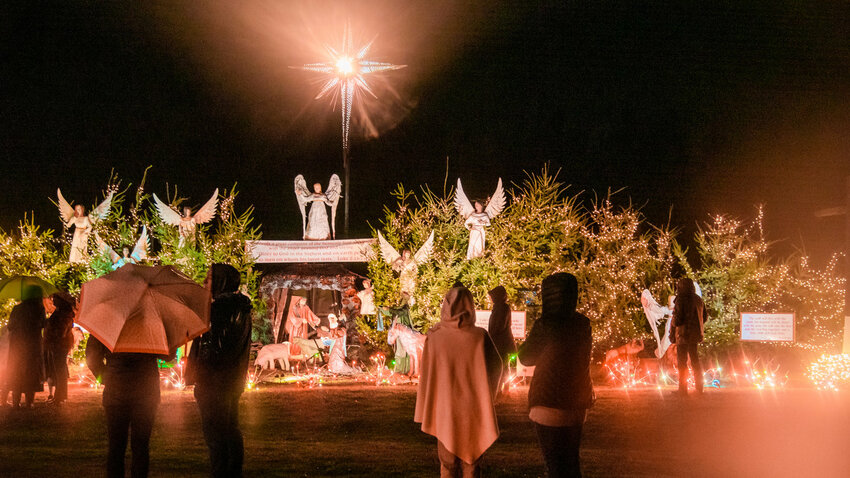 Visitors gather, some holding umbrellas as rain falls, during the Christmas Island Lighting Ceremony in Maytown in 2021.