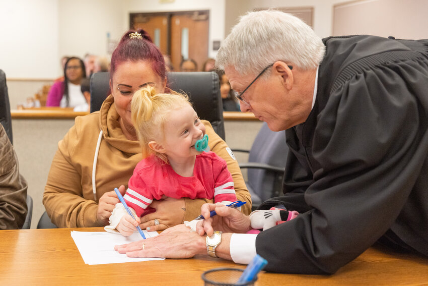 Judge James W. Lawler talks to the Williams family as they sign paperwork for adoption in Lewis County Superior Court Friday afternoon in Chehalis.