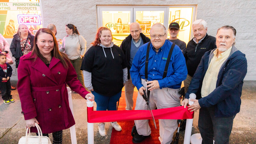 Daryl Lund smiles as he prepares to cut a ribbon at Minuteman Press in Chehalis alongside family, friends, employees and city councilors on Tuesday, Dec. 12.