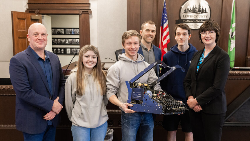 From left, Commissioner Scott Brummer, Phoebe Allen, Nate Scheuber, Commissioner Sean Swope, Zane Gaffney and Commissioner Lindsey Pollock smile for a photo after students with the Adna Robotics program share a demonstration with attendees during a Tuesday meeting inside the Lewis County Courthouse in Chehalis.