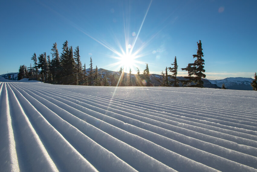 The sun is seen descending in the western sky over groomed corduroy patterns in the snow at the White Pass Ski Area on Saturday, Dec. 23.