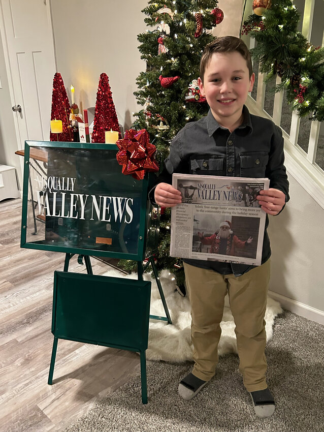 Greyson Jewell poses with a copy of the Nisqually Valley News and a dispenser.