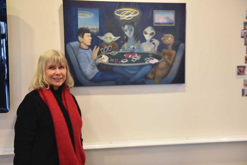 Local artist Cari Thompson, whose art work is displayed in Olympia at the Thomas Architecture Studios, smiles in front of one of her paintings on Jan. 29.