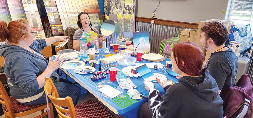 Denise Champion, Kara Welsh and participants at a workshop at Rodda Paint in Battle Ground, Feb. 1, exchange a laugh as they practice painting sky-like gradients.