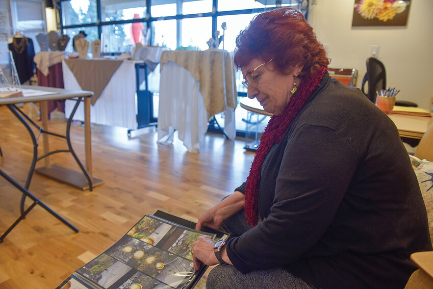 Jewelry artist Lois Steiner flips through a binder containing photographs of the art she&rsquo;s created over the years.