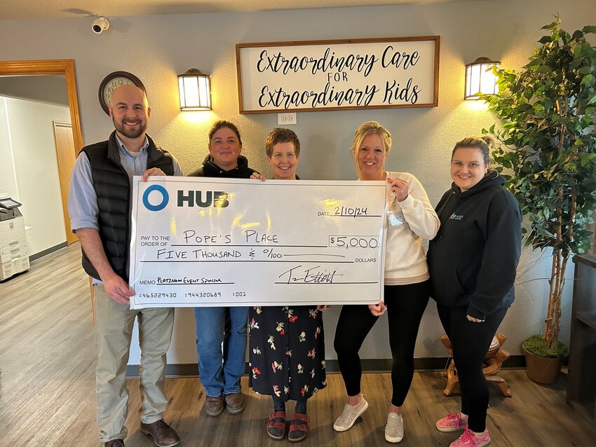 Trevor Elliott, a senior advisor of insurance from HUB Northwest Insurance in Chehalis, at left, presents a check to Pope&rsquo;s Place staff last week.