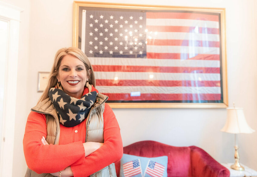 Leslie Lewallen smiles for a photo in front of a flag that flew over the White House Tuesday morning at her Camas home.