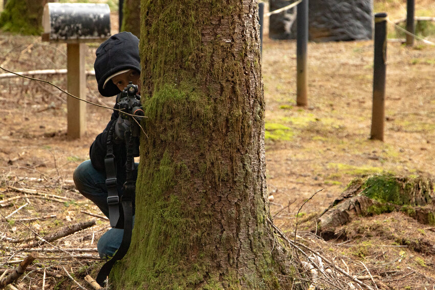 Ayden Westlund of Adna uses a tree for cover durign airsoft games held at The Huntting's Pumpkin Patch and Haunted Forest in Cinebar on Saturday, Feb. 17.