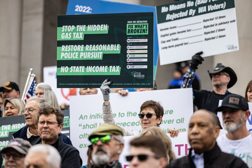 People hold signs during the &ldquo;Let&rsquo;s Go Washington&rdquo; initiatives rally at the Capitol in Olympia on Friday, Feb. 23, 2024.