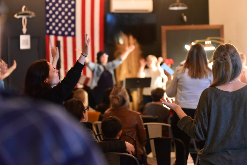 Spectators hold their arms in the air as they praise Jesus at Worthy Coffee Co.'s Sunday Worship event on Feb. 25.