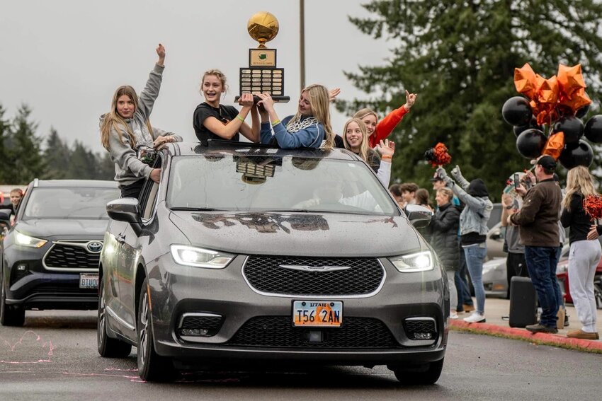 Members of the Napavine girls basketball team hold the 2B State Championship trophy as they roll through Napavine to cheers from family and community members on Sunday. The team defeated Okanogan in the state championship game at the Spokane Arena on Saturday night.