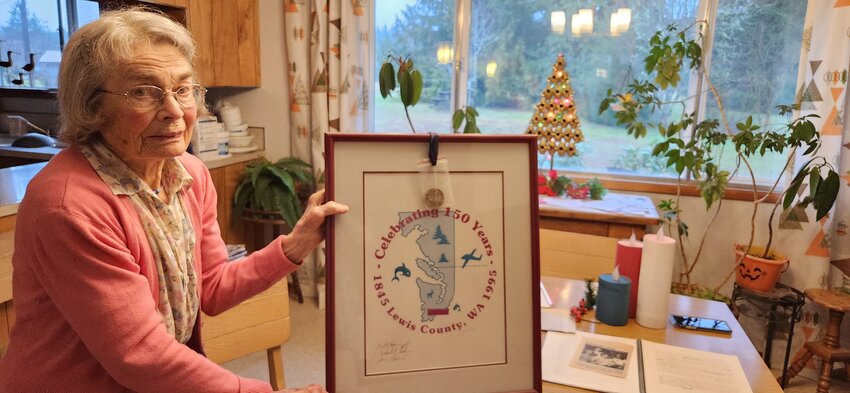 Margaret &ldquo;Denny&rdquo; (Kirkendoll) Cole, of Ethel, poses with the logo she created to commemorate Lewis County&rsquo;s sesquicentennial in 1995.