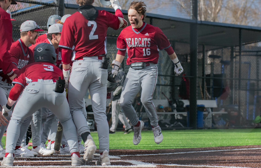 Deacon Meller leaps ahead of home plate surrounded by teammates after a lead-off home run during W.F West's 4-2 win over Timberline on March 12 at Centralia College.