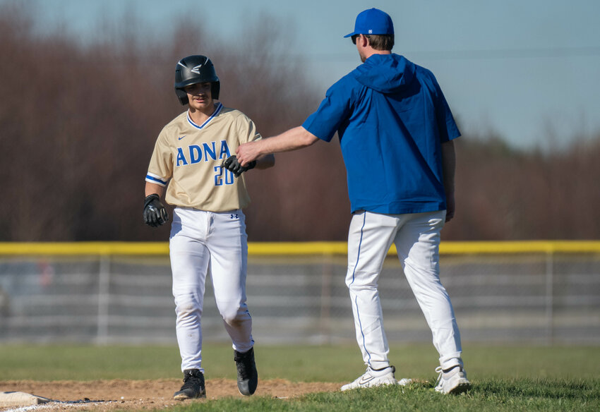 Nailon Ramirez fist bumps his first base coach after hitting a single during a doubleheader between Adna and Winlock on Monday March 18 in Winlock.