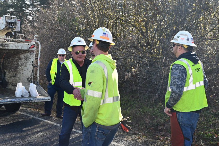 Lewis County Public Utility District Commissioner Michael Kelly shakes hands with members of one the PUD&rsquo;s tree trimming crews.