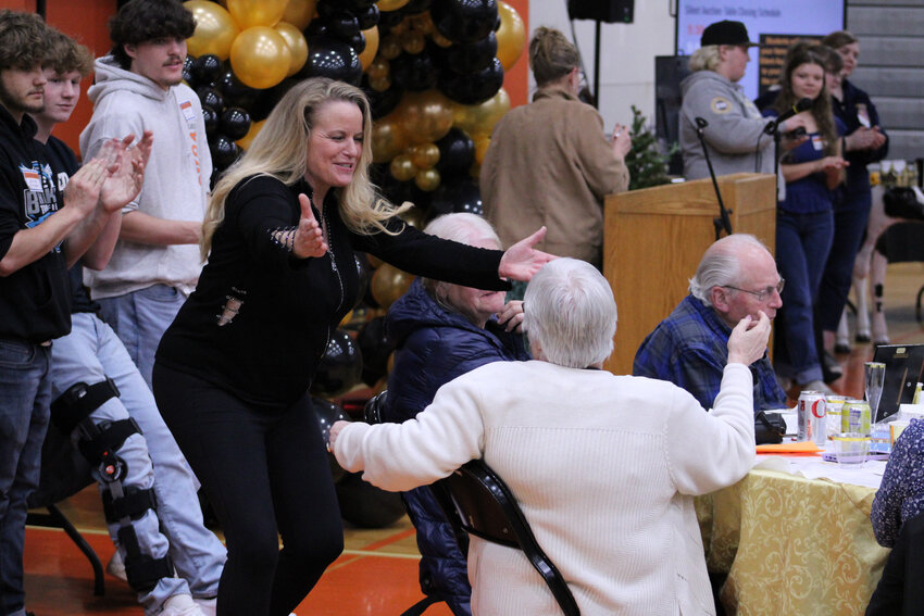 Auctioneer Cindy Schorno (left) offers to hug a community member who purchased an item during the auction.