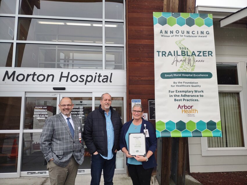 Arbor Health quality leaders stand next to an award-announcement banner at the Morton Hospital entrance. From left, Chief Executive Officer Robert Mach, Chief Medical Officer Kevin McCurry  and Quality Department Manager Julie Johnson.