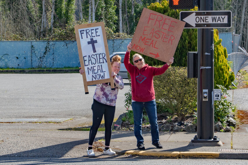 Chevron Manager and Lewis County Drug Court graduate Leah Rader of Napavine, left, stands next to her friend, Kristina Lopes of Napavine, as they hold signs advertising free hot meals they were handing out on Easter Sunday, March 31, at the Centralia Chevron.
