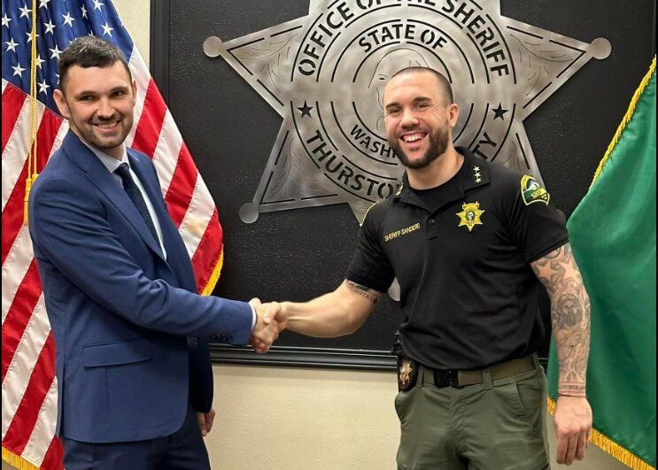 Thurston County Sheriff Derek Sanders, right, shakes Christopher Burbank&rsquo;s hand in this photo posted to the Sheriff&rsquo;s Office Facebook page. Burbank was one of three officers acquitted in December of the shooting death of Manny Ellis in 2020 in Tacoma. Burbank was hired as a lateral patrol deputy.  The Thurston County Sheriff&rsquo;s Office announced Wednesday that Burbank had resigned after the department faced backlash for hiring him.