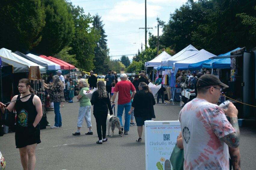 Customers walk throughout the Yelm Farmers Market on Saturday, May 27, 2023.