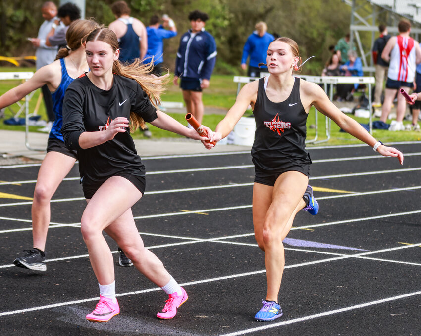 Battle Ground&rsquo;s Lucy Smith, right, hands the baton off to Charlotte Clarke during the girls 4x200-meter relay at the John Ingram Twilight Track and Field Meet on Friday, April 12.