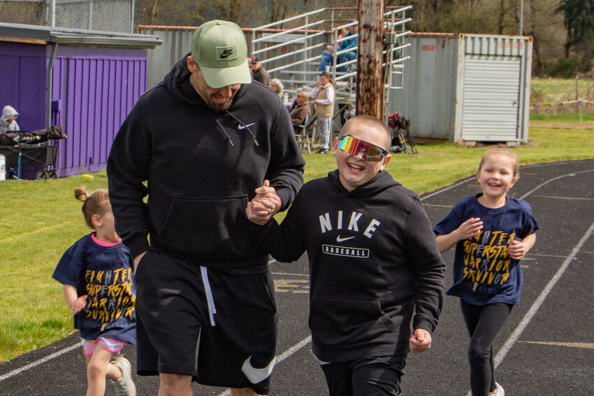 Brody Hamilton laughs and runs alongside his father, Chris, during a Walk with Reason fundraiser event on Saturday, April 13, at the Onalaska High School track.