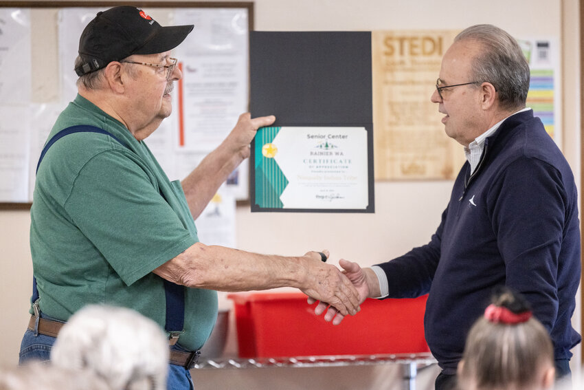 George Johnson, left, shakes hands with Bob Iyall at the Rainier Senior Center on Wednesday, April 10.