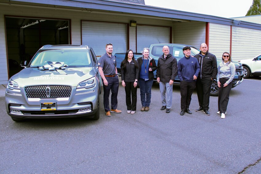 Dawn Kraves and Chris Woods (center) pose for a photo with members of Mullinax Ford and the Yelm High School automotive program's new 2023 Lincoln Aviator on April 11.