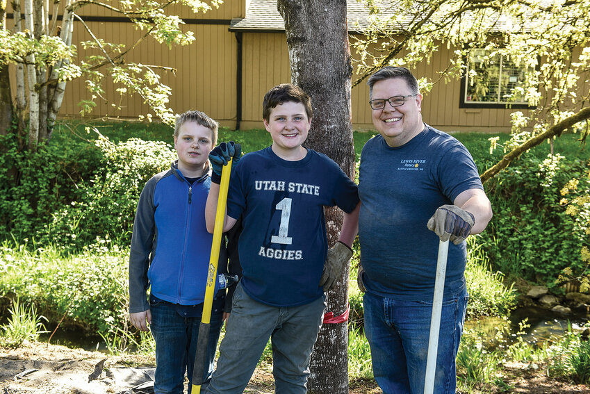 Neil Butler (right), James Butler and Andrew Butler, members of the Lewis River Rotary Club, removed weeds surrounding the pond in Central Park.