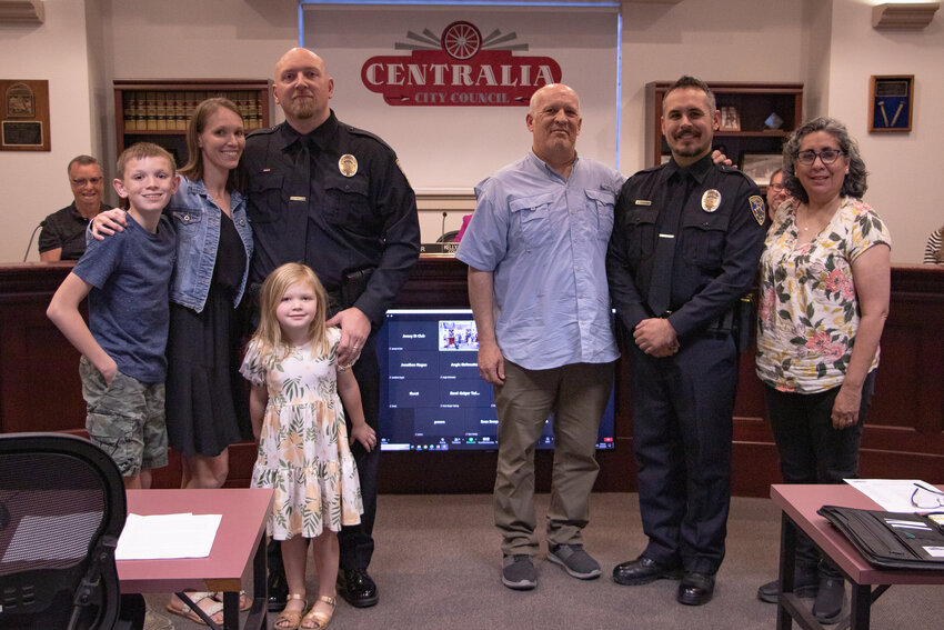 On the left, Centralia police officer Emmet Woods poses with his wife, Sheena, and their children, Rory and Reese, while  Centralia police officer Alan Bowers, on the right, stands with his parents, Chuck and Lupe, after both officers were sworn in during the Tuesday, April 23, Centralia City Council meeting.