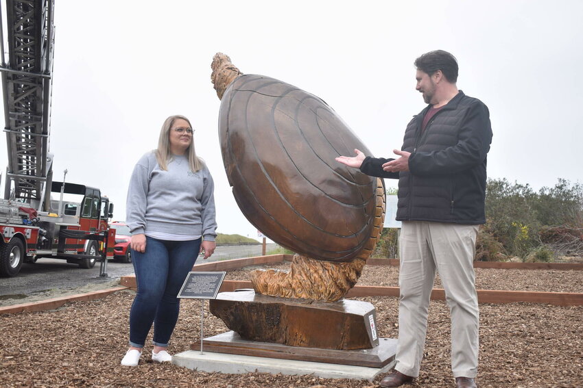 Ocean Shores City Clerk Sara Logan, left, and City Administrator Scott Andersen unveil Anthony Robinson&rsquo;s giant razor clam statue near the Chance A La Mer beach entrance on Wednesday, April 24.