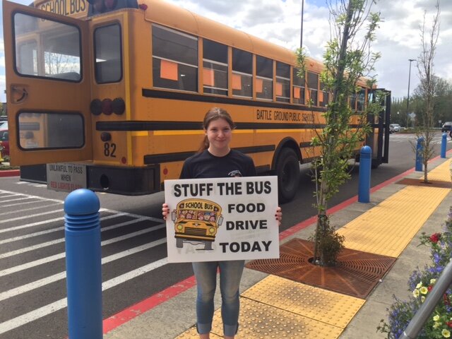 A volunteer stands with a sign at the annual “Stuff the Bus” food drive, which collects items and cash donations for the North County Community Food Bank.